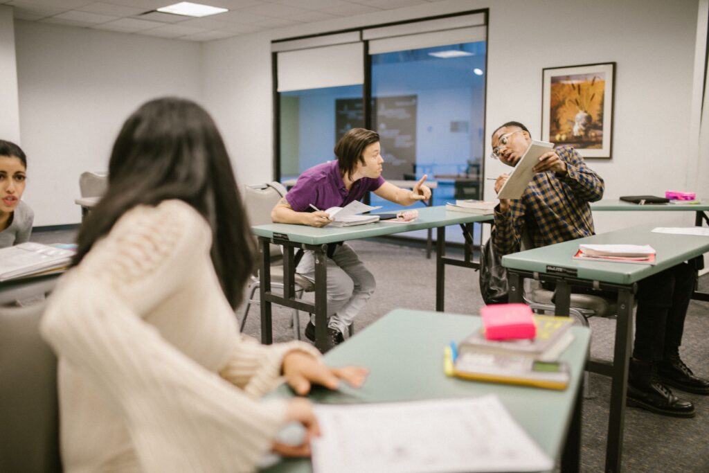 College students engaging in conversation during class, indicating collaboration and learning.